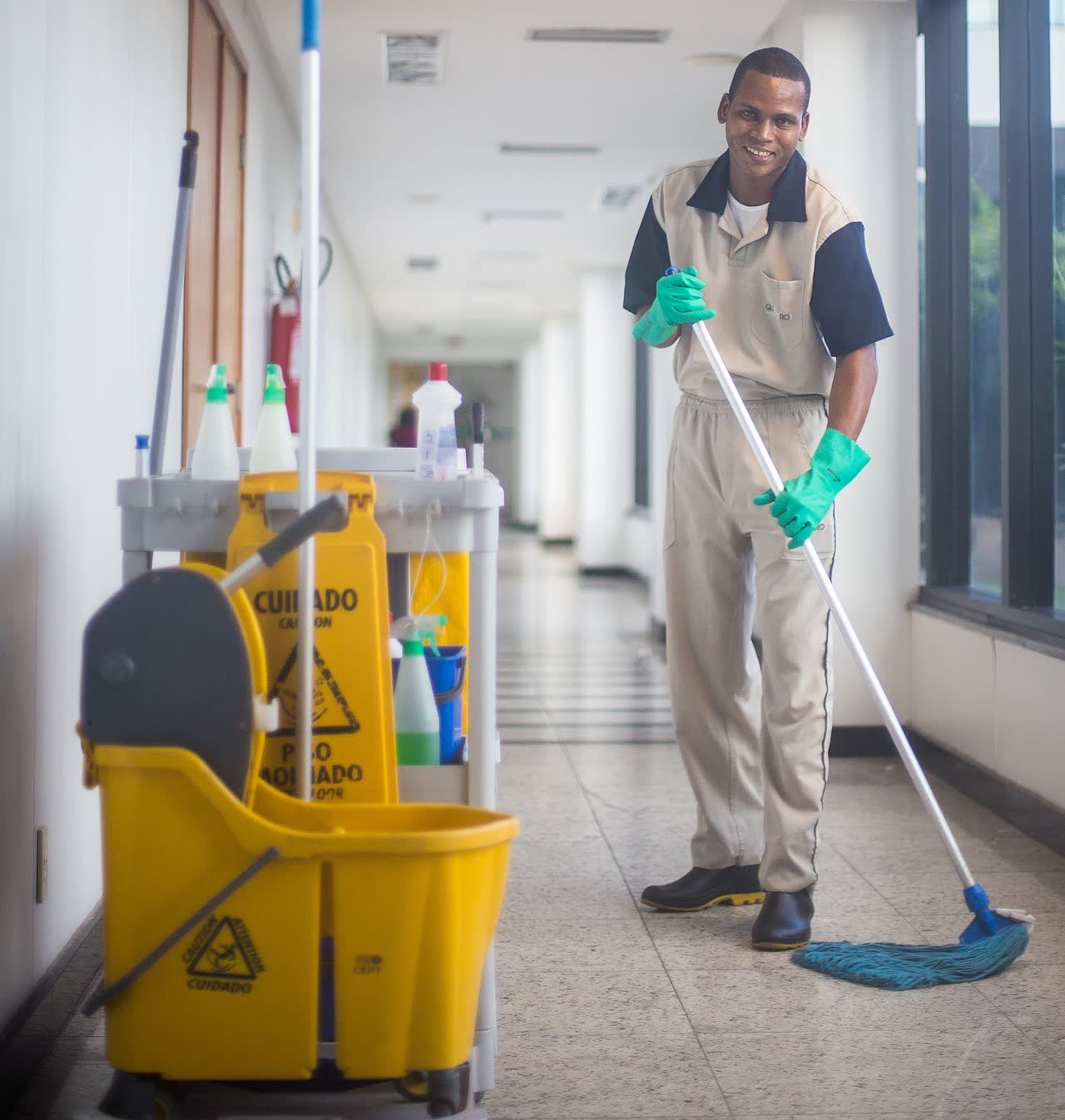 Friendly sanitation worker mopping a hallway floor
