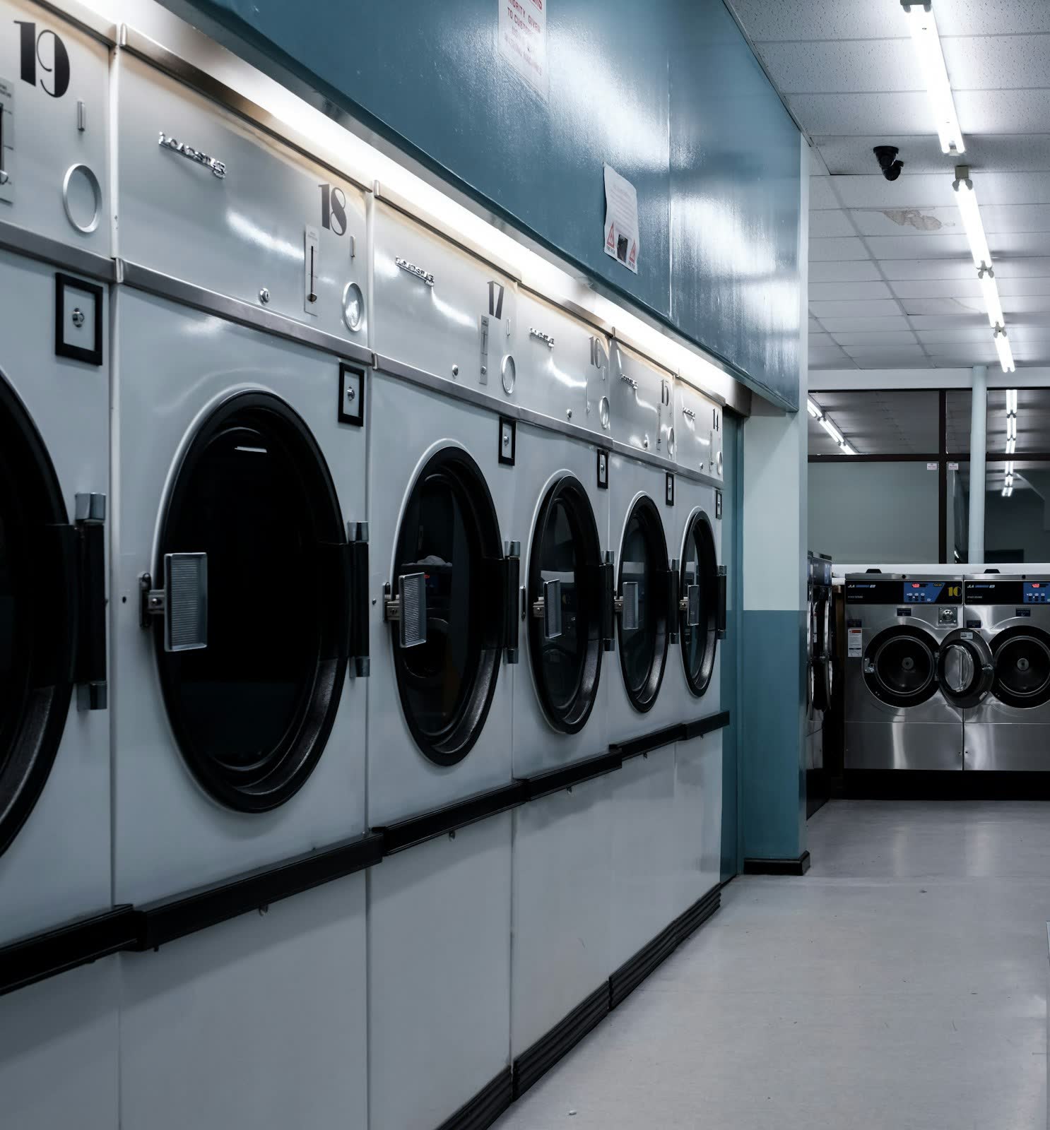 Industrial washing machines and dryers along a wall